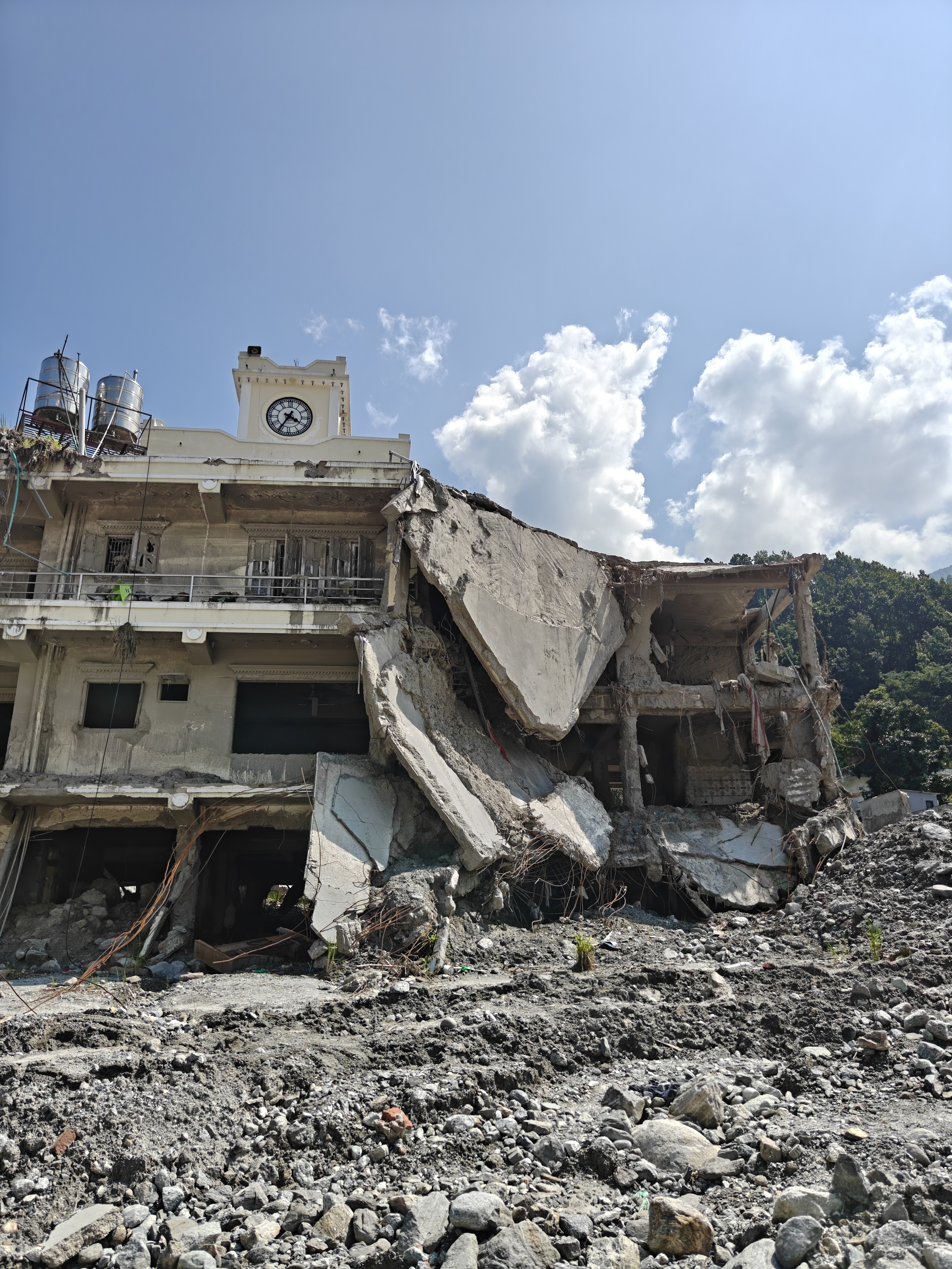 A collapsed building surrounded by flood debris in Rasuwa, Nepal