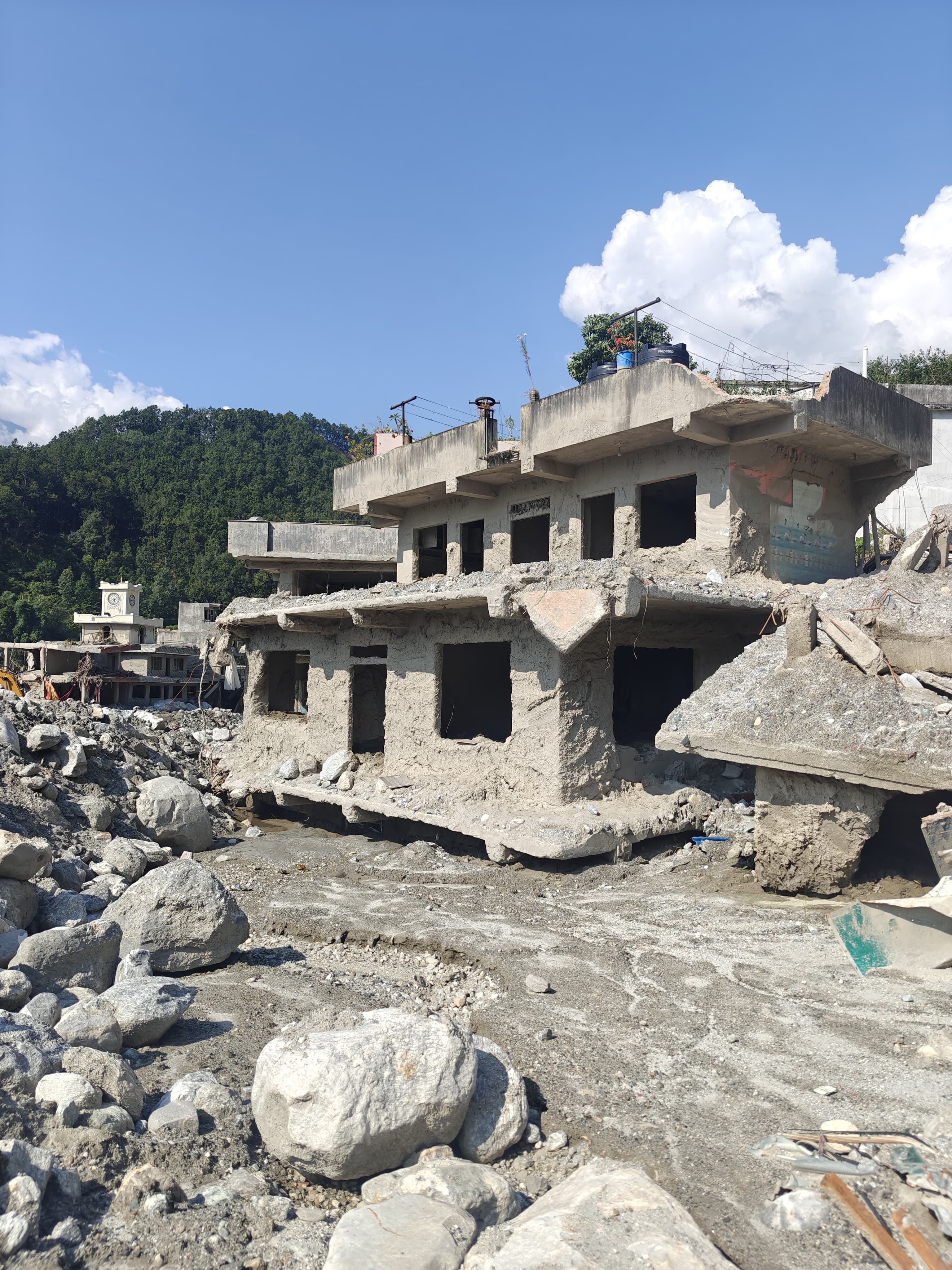 Flood-affected river corridor and damaged buildings in Rasuwa